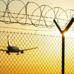 Airport behind guard fence in sunset